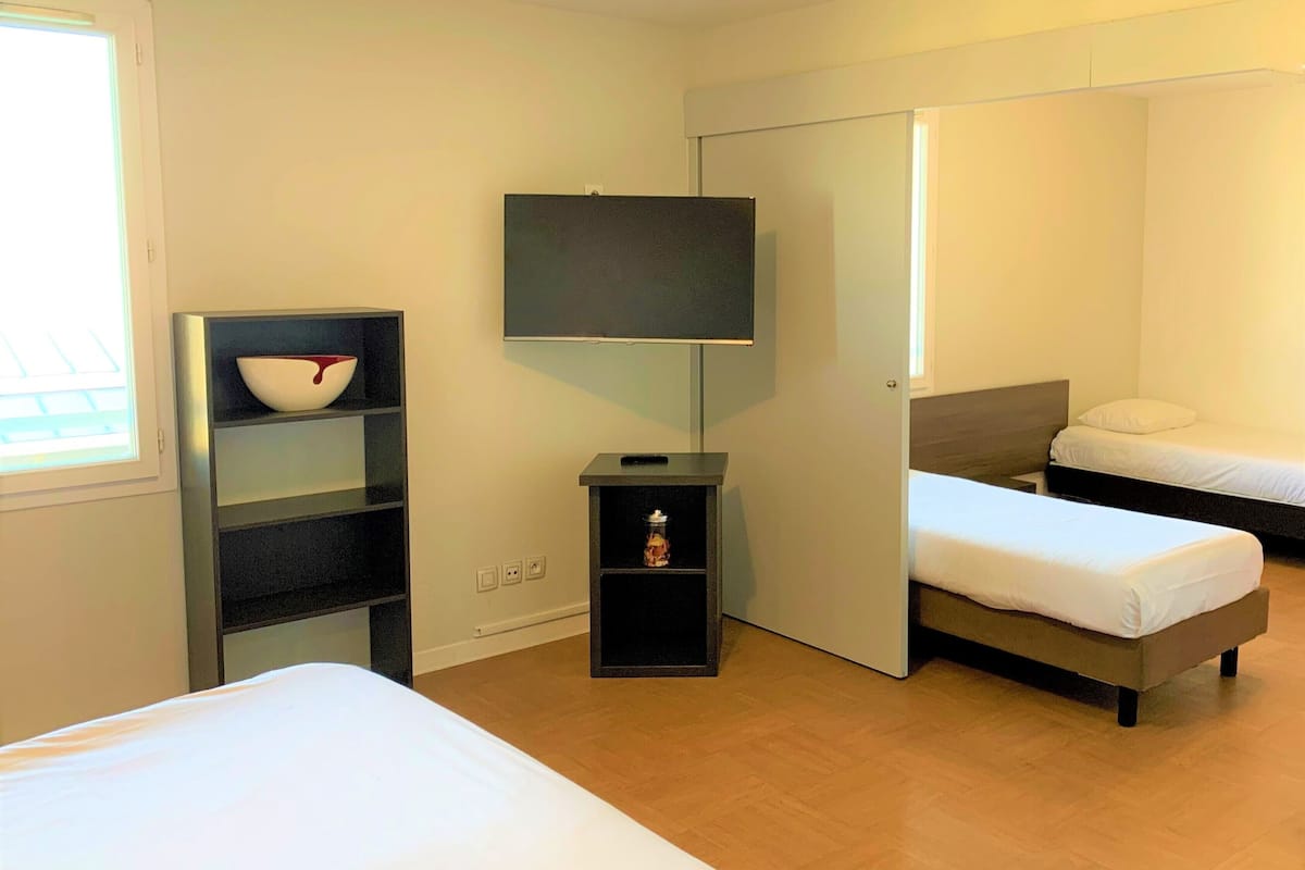 A bedroom with a bed, a TV, a shelf with a bowl, and a wardrobe.