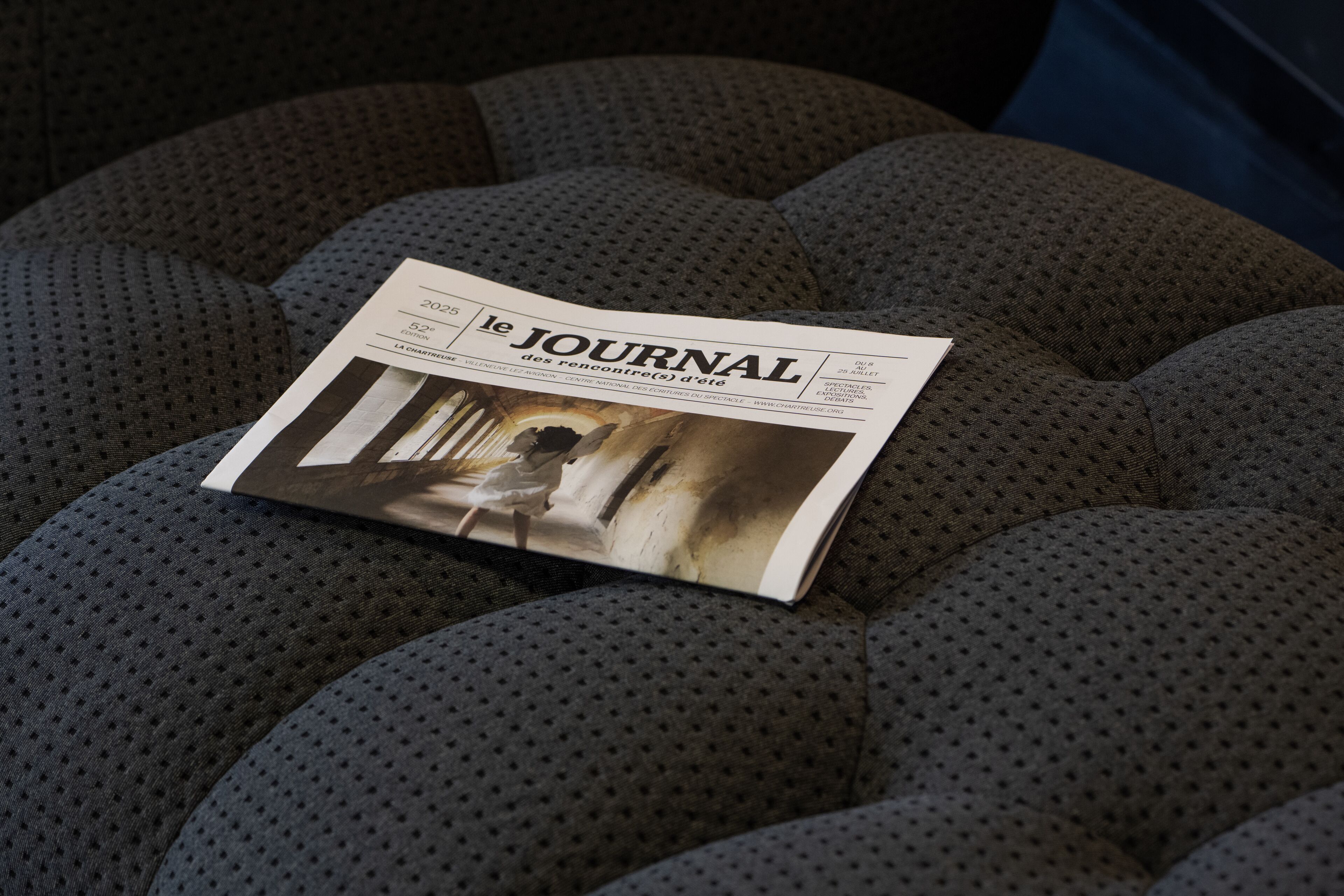 A magazine titled "le JOURNAL" on a textured grey sofa.