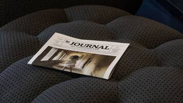 Una revista titulada "le JOURNAL" sobre un sofá gris con textura.