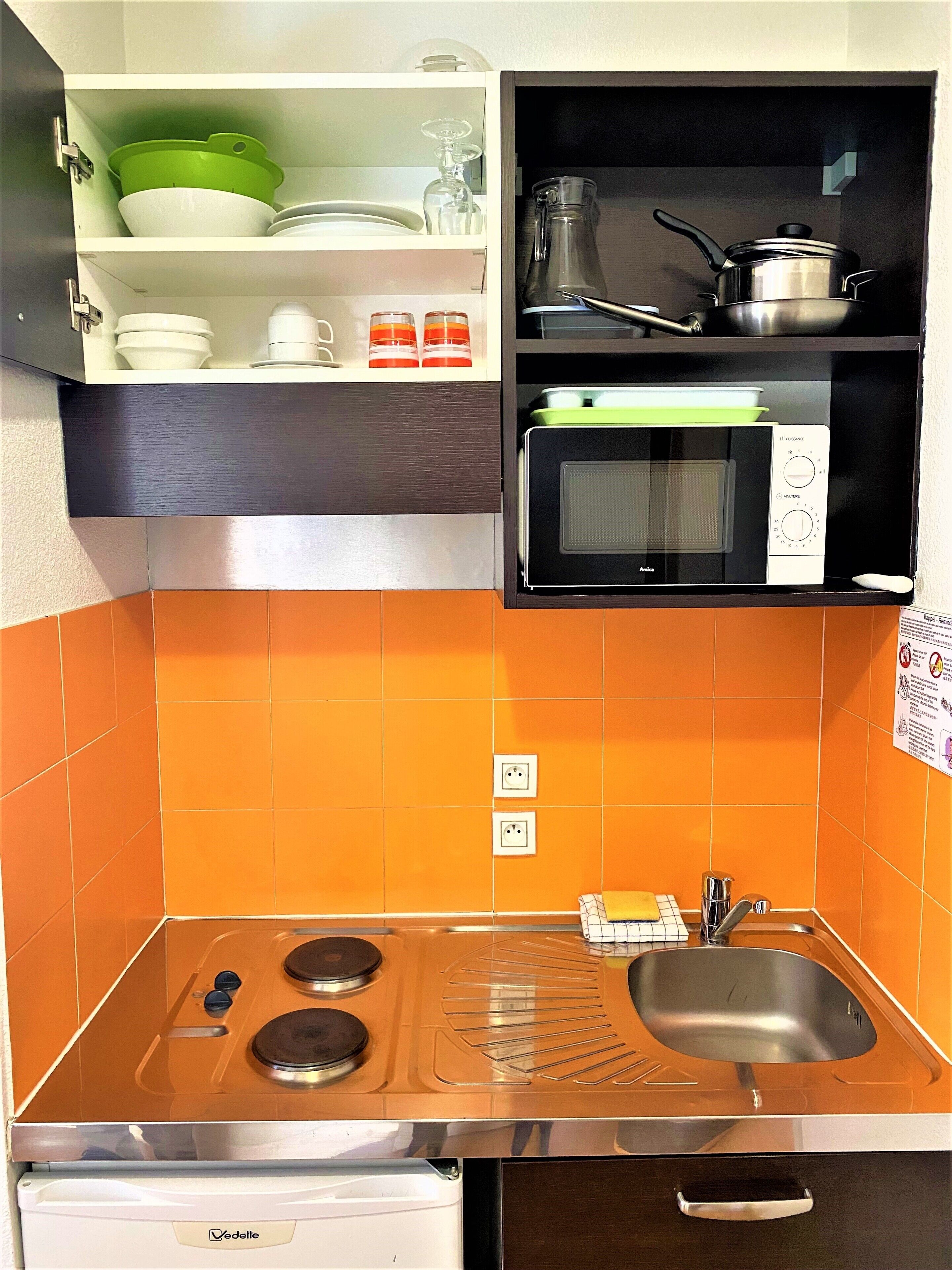 Een kleine keuken met een fornuis, spoelbak en magnetron.