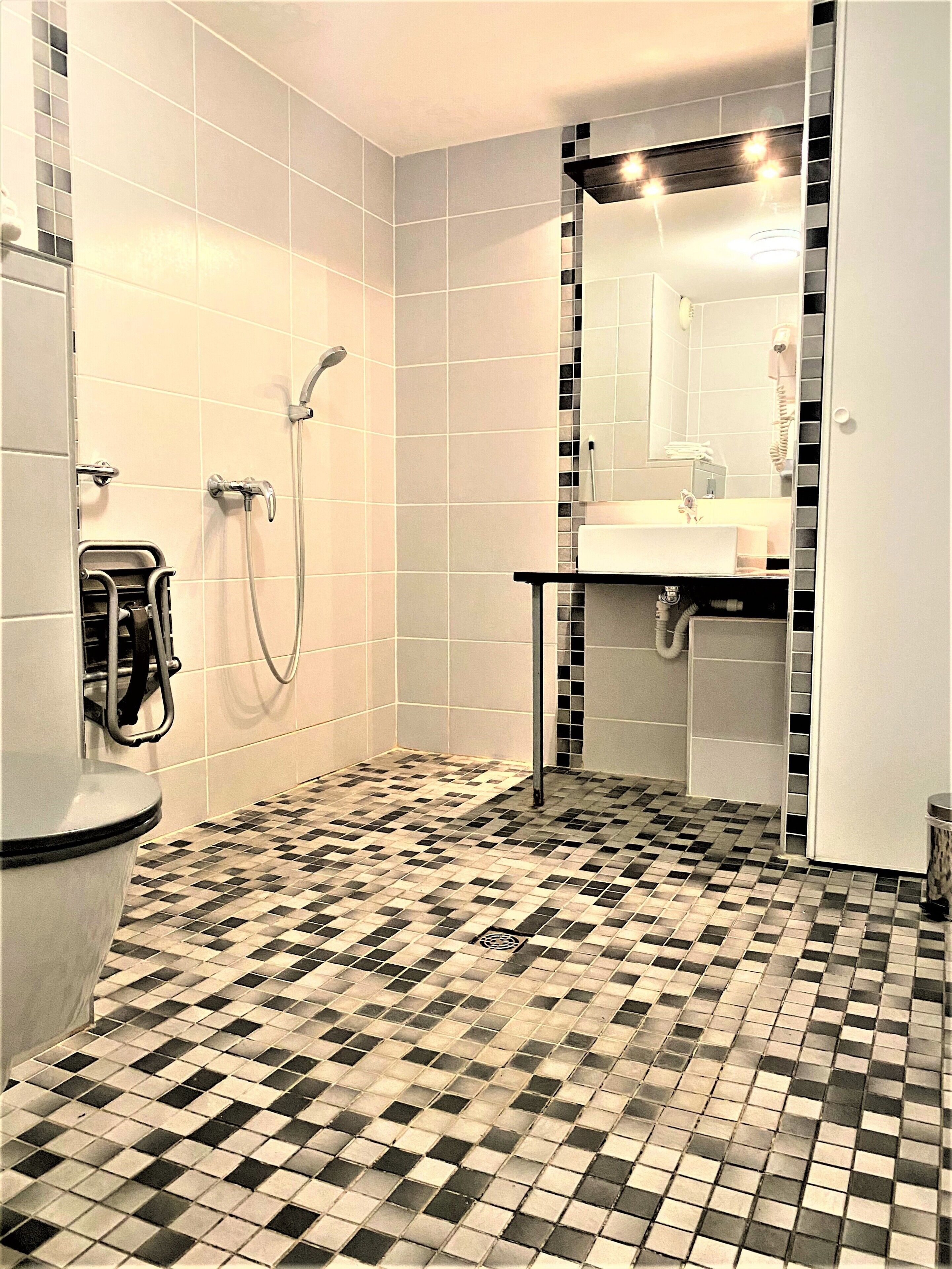 A bathroom with a checkered floor, a toilet, a sink, and a shower.