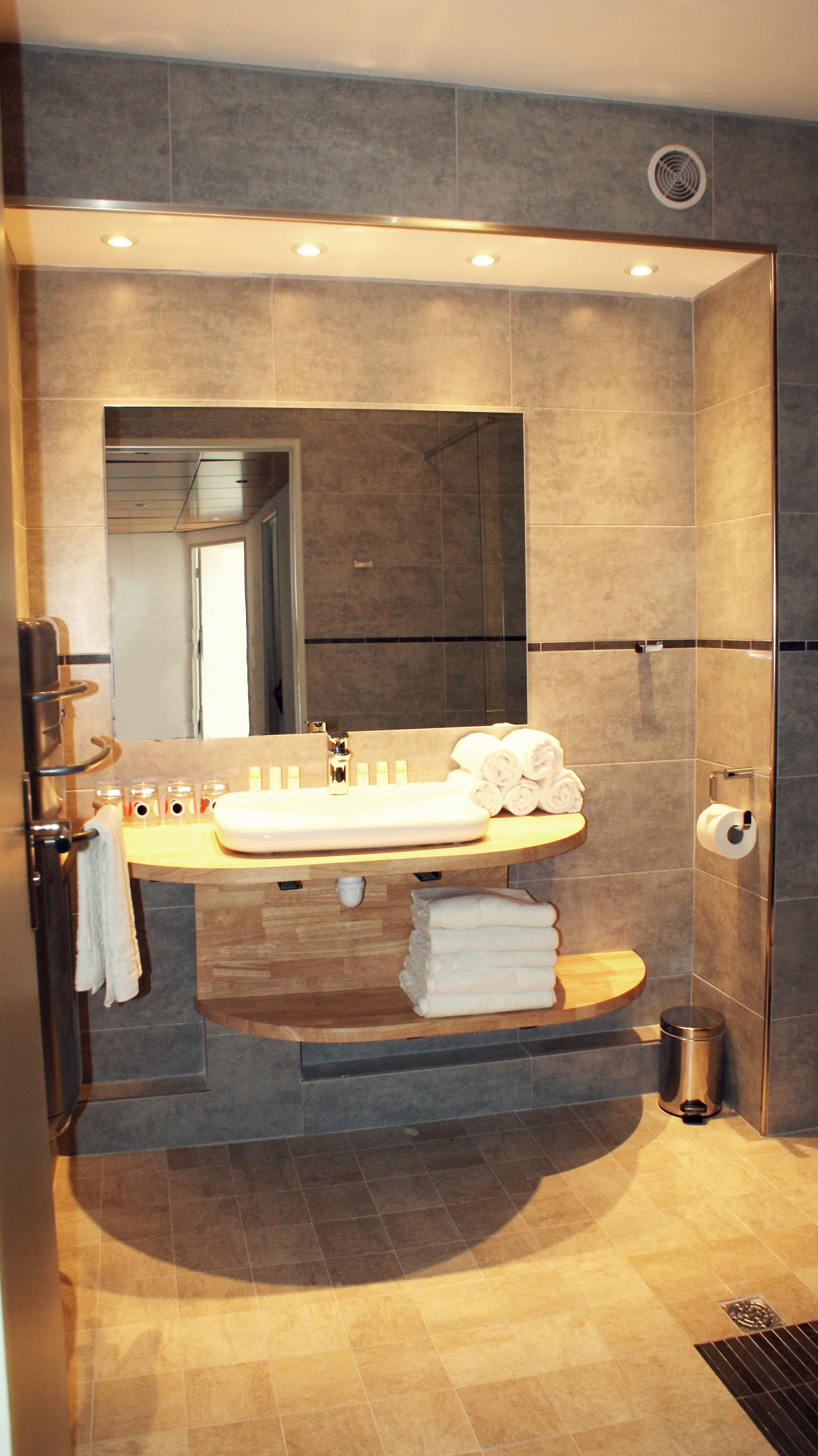 A modern bathroom with a large mirror, a sink, and a toilet.