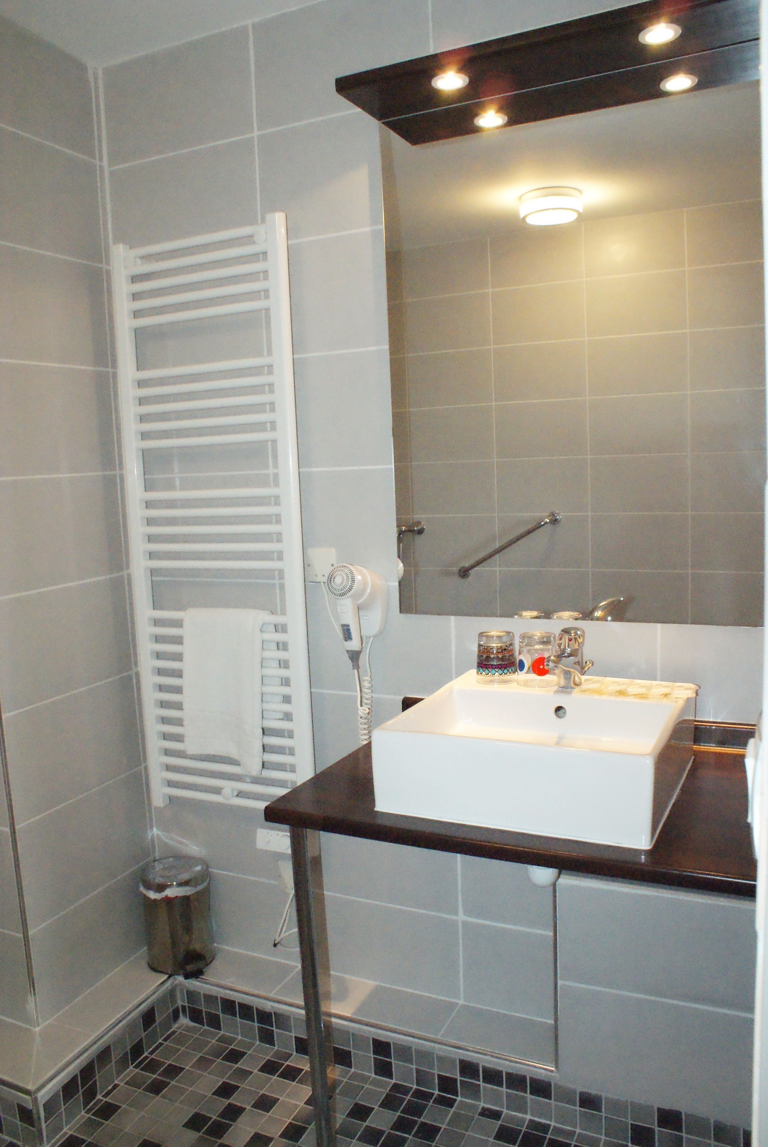 A bathroom with a white sink, mirror, and towel rack.