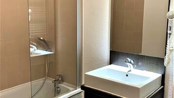 A modern bathroom with a glass-enclosed shower, a white sink, and a mirror above it.