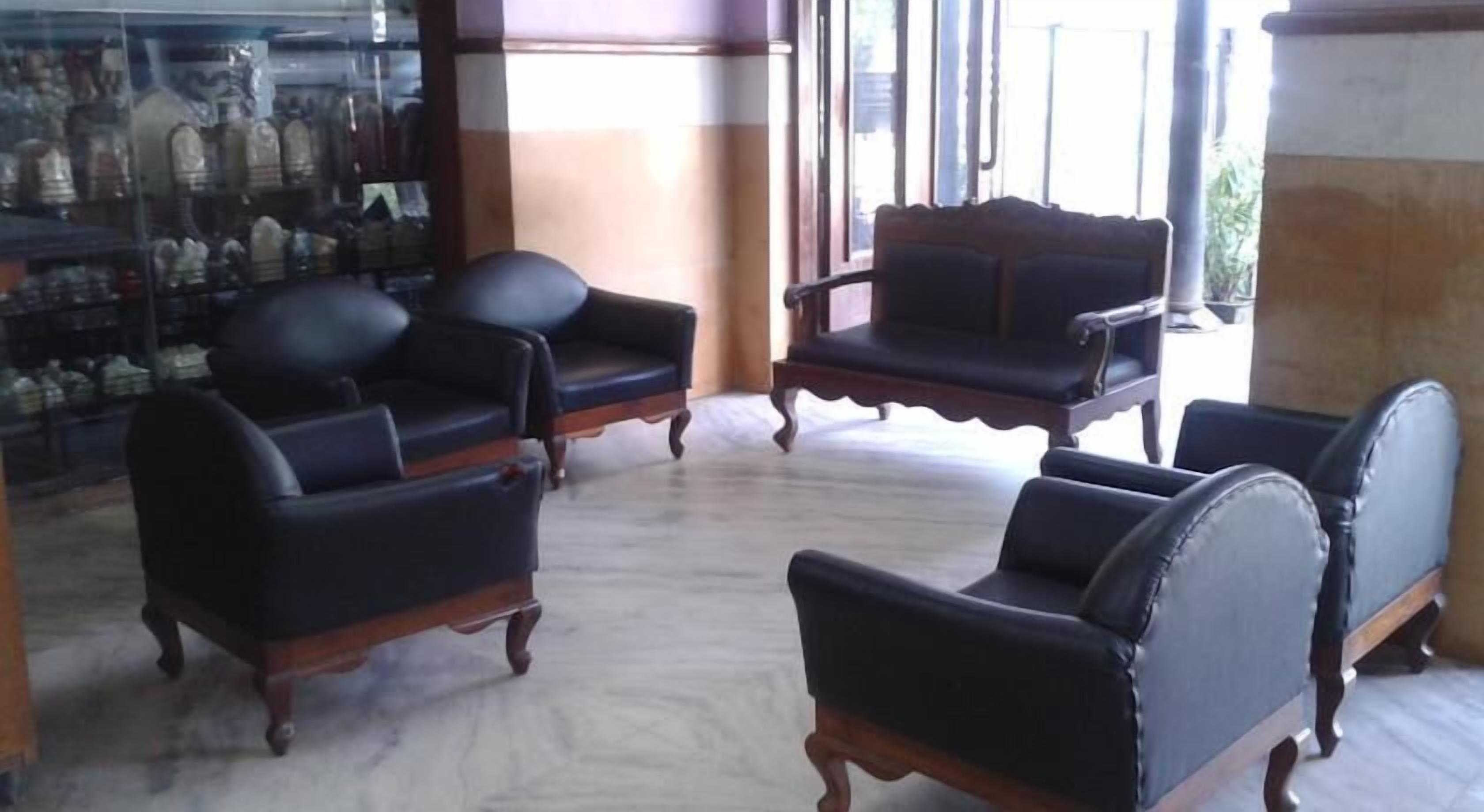 A seating area with four black leather armchairs and a wooden coffee table.