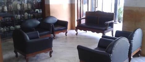 A seating area with four black leather armchairs and a wooden coffee table.