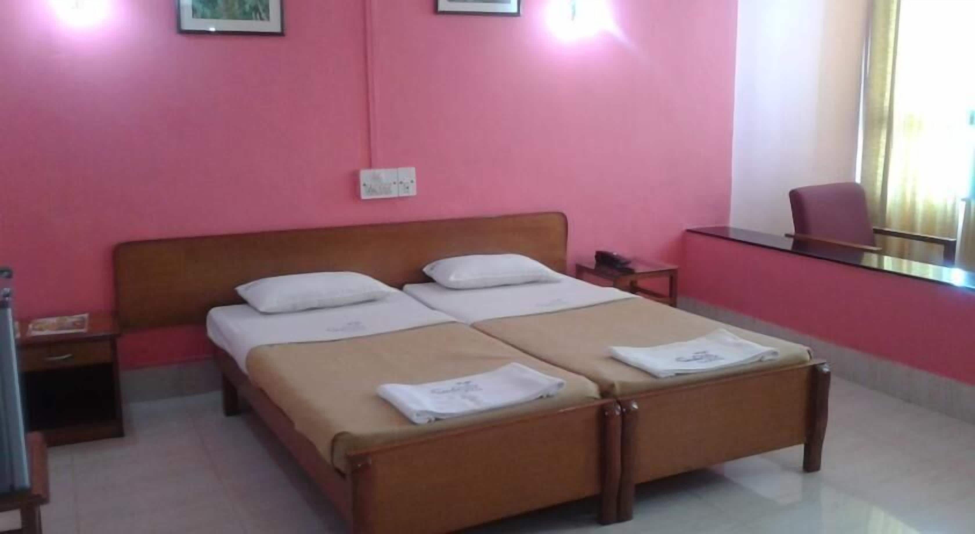 A double bed with two pillows, a bedside table, a chair, and a desk with a chair.