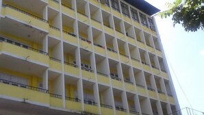 Un edificio de varios pisos con fachada amarilla y balcones blancos.