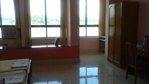 Una habitación con cama, escritorio y armario. Hay ventanas con cortinas.