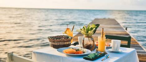 A table set with breakfast items and a drink, overlooking the sea.