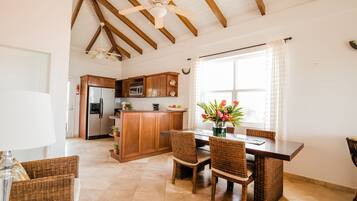 Una cocina amplia con armarios de madera, una isla central y una zona de comedor con sillas de mimbre.