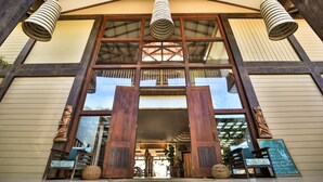 A building entrance with large wooden doors, a hanging light fixture, and a view into the interior. - Umaya Resort & Adventures (Placencia)
