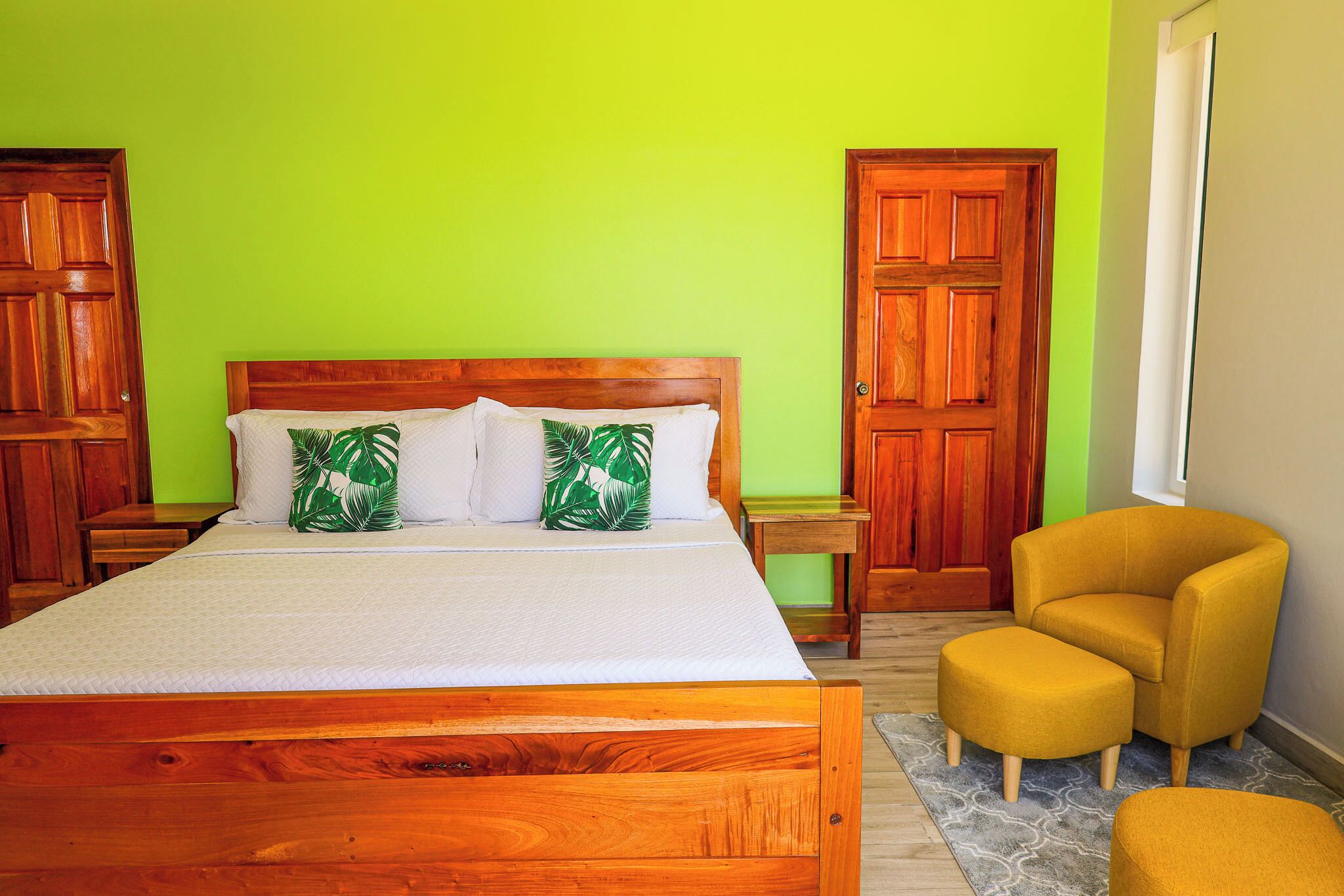 A bedroom with a wooden bed, green walls, and a yellow armchair.