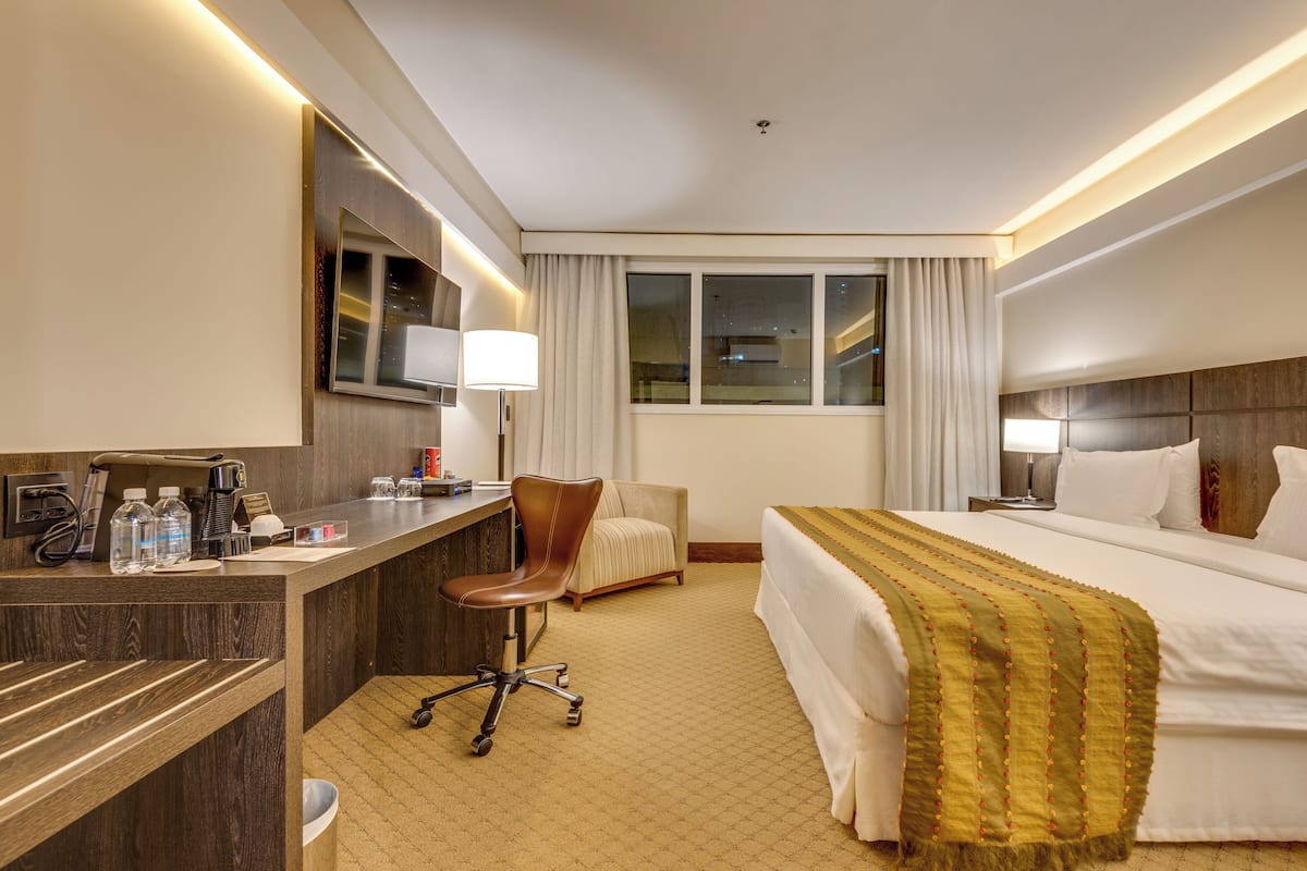 Una habitación de hotel con cama, escritorio, silla y ventana.