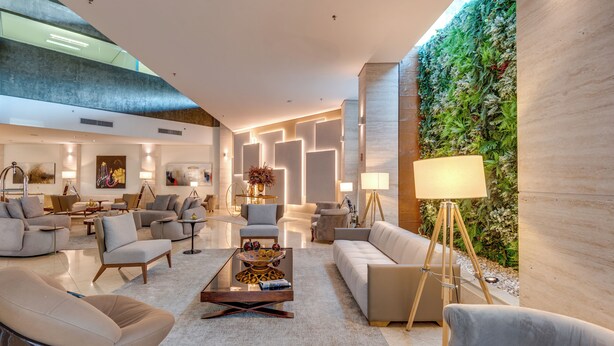 A spacious, modern living area with a high ceiling, contemporary furniture, and a vertical garden wall.