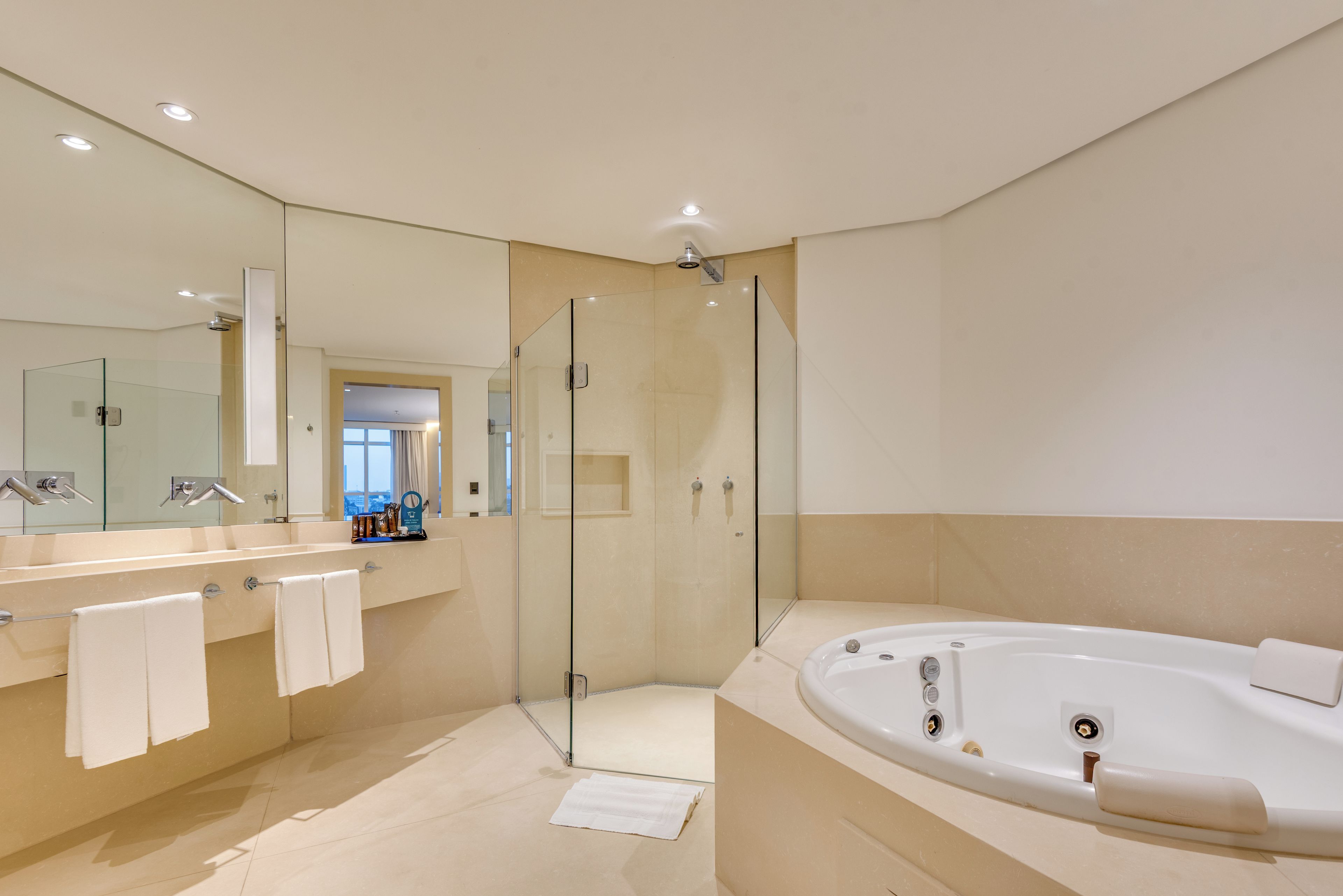 A modern bathroom with a glass-enclosed shower, a large bathtub, and a vanity with a mirror.