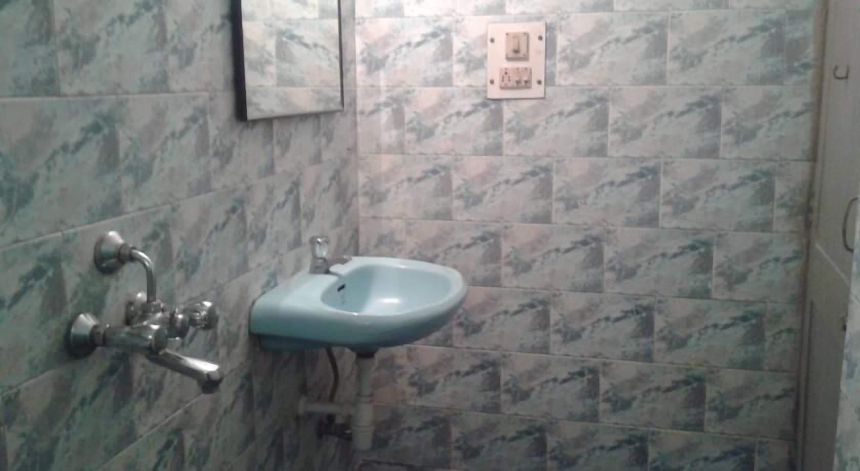 A bathroom with marble tiles, a sink, and a faucet.