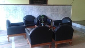 Un hall con zona de estar, compuesto por cuatro sillas de cuero negro y una mesita con planta en maceta.
