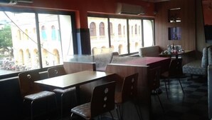 Un restaurante con vista a un edificio de arcos, mesas y sillas, y una barra.