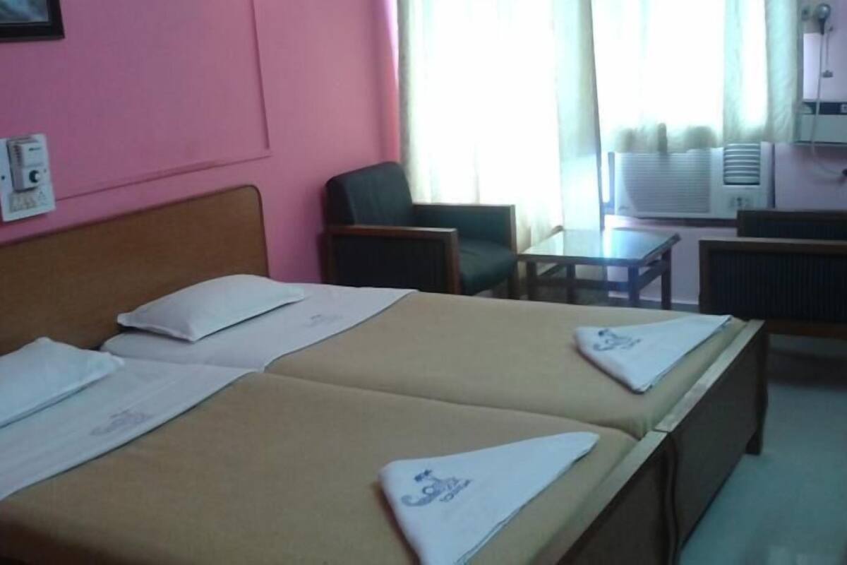 A hotel room with two beds, a desk, and a chair.
