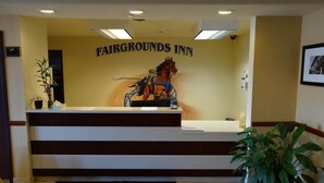 Una recepción con el letrero 'FAIRGROUNDS INN' y una obra de arte con caballos sobre ella.