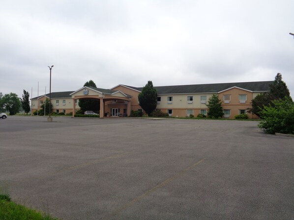 A large, multi-story hotel with a central entrance and a parking lot.