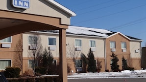 Edificio del Fairgrounds Inn con fachada color beige, múltiples ventanas y un techo cubierto de nieve.