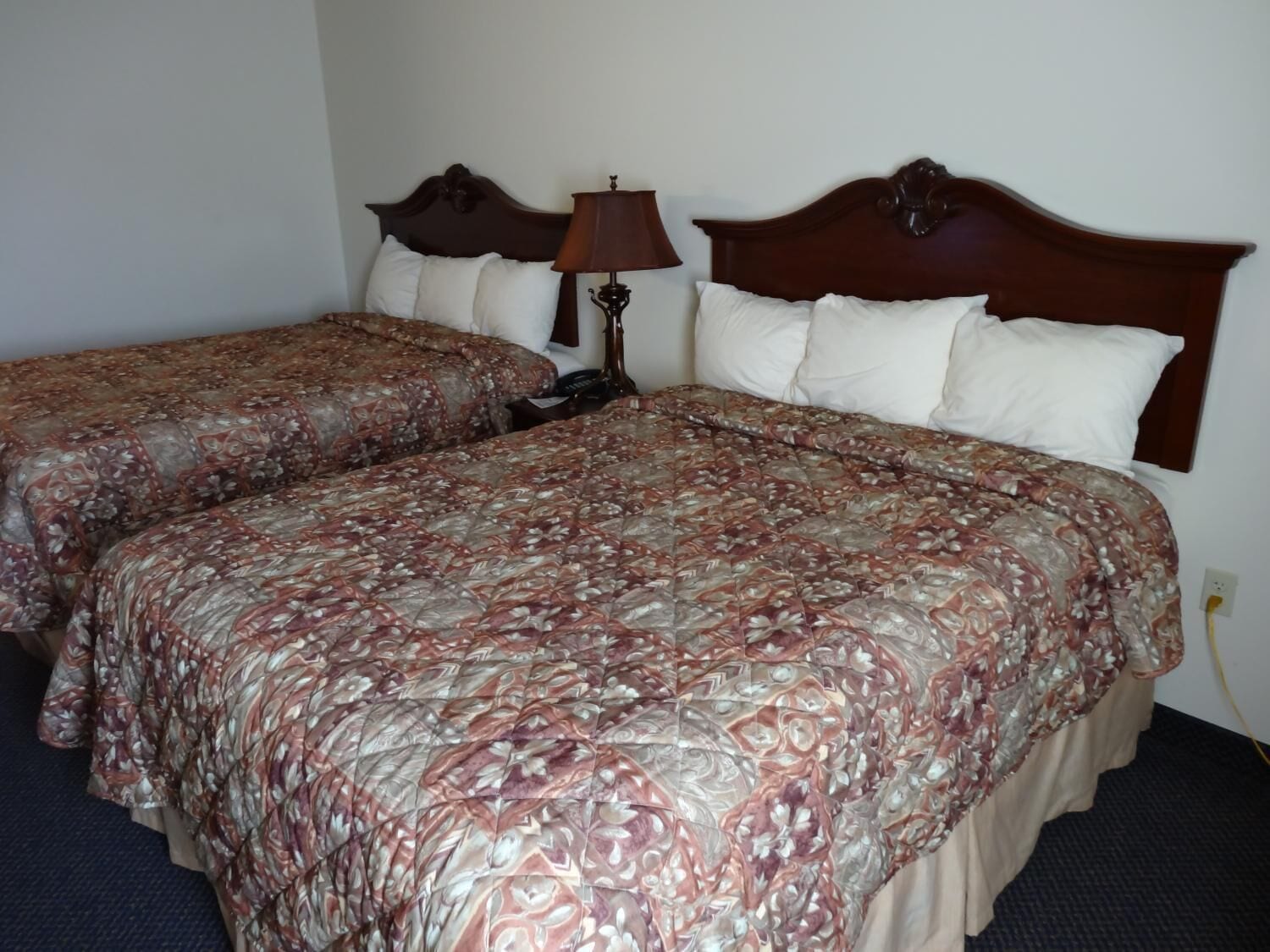 A double bed with a floral bedspread and a nightstand with a lamp.