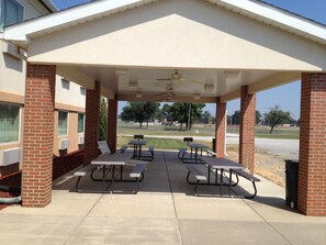 An outdoor covered patio with picnic tables and a ceiling fan.