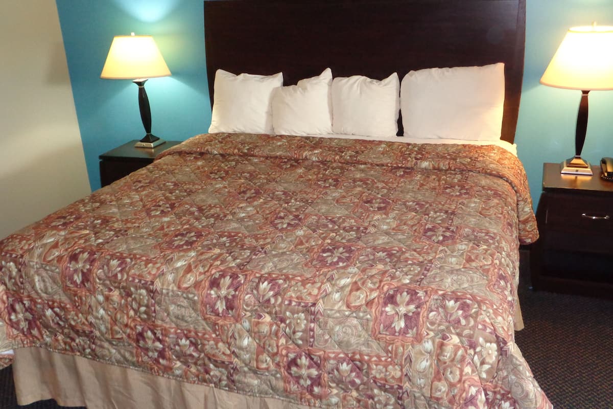 A bed with a patterned bedspread, two bedside lamps, and a dark headboard.