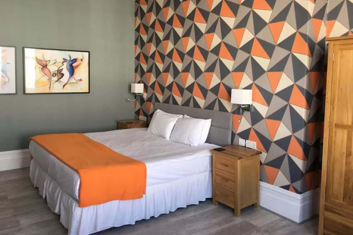 A hotel room with a bed, nightstands, and a geometric patterned wall.