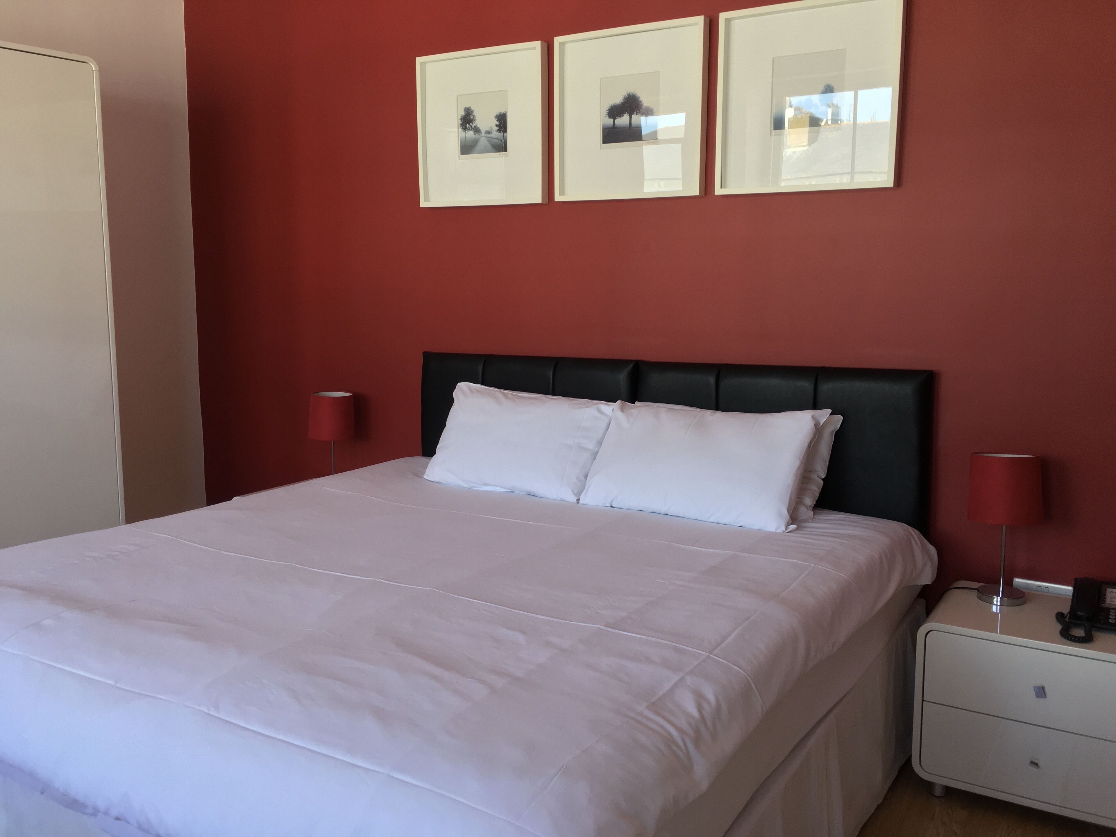 A neatly made bed with white linens, a black headboard, and two bedside lamps.