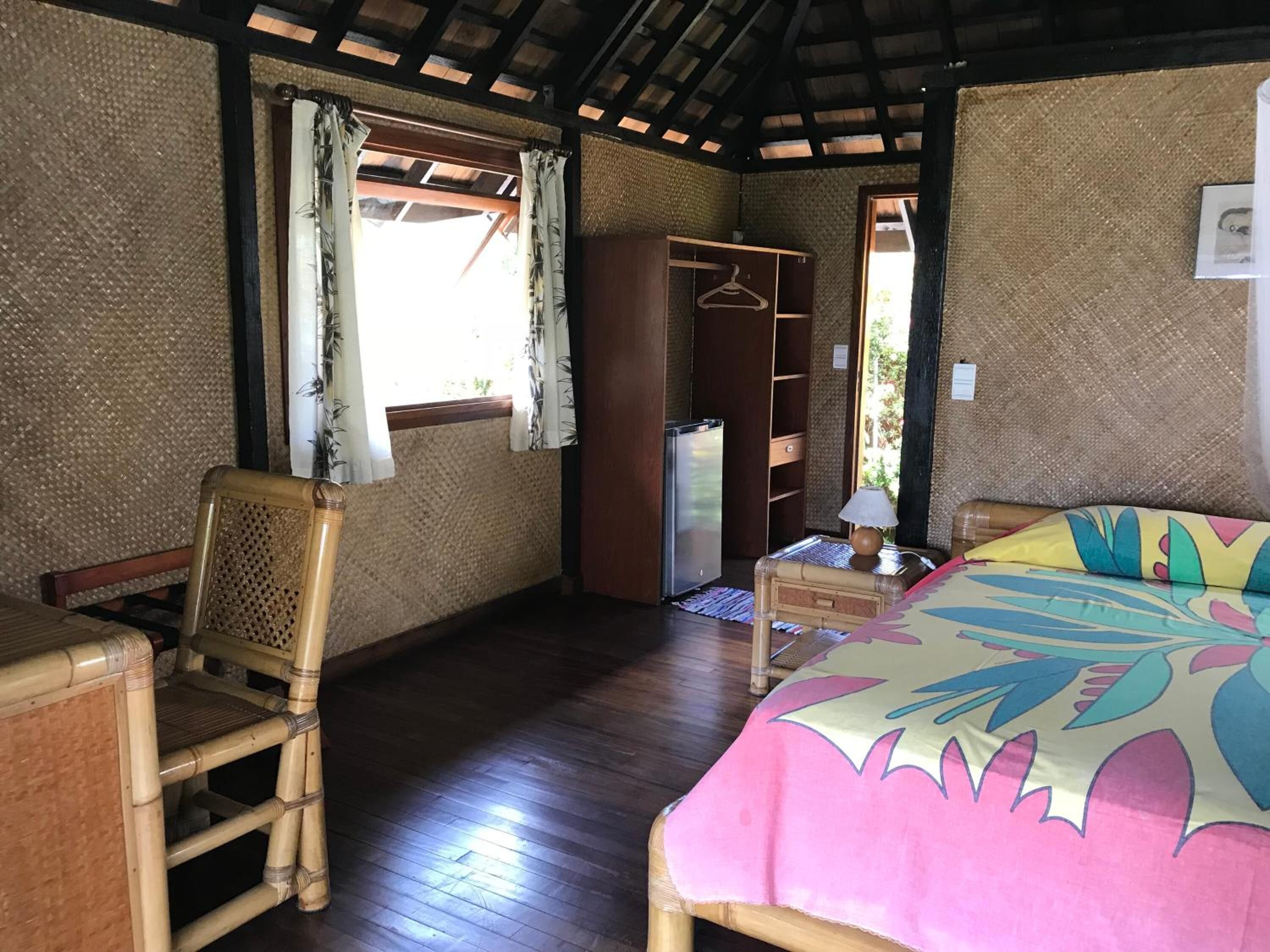 A room with a bed, a chair, a wardrobe, and a small table.