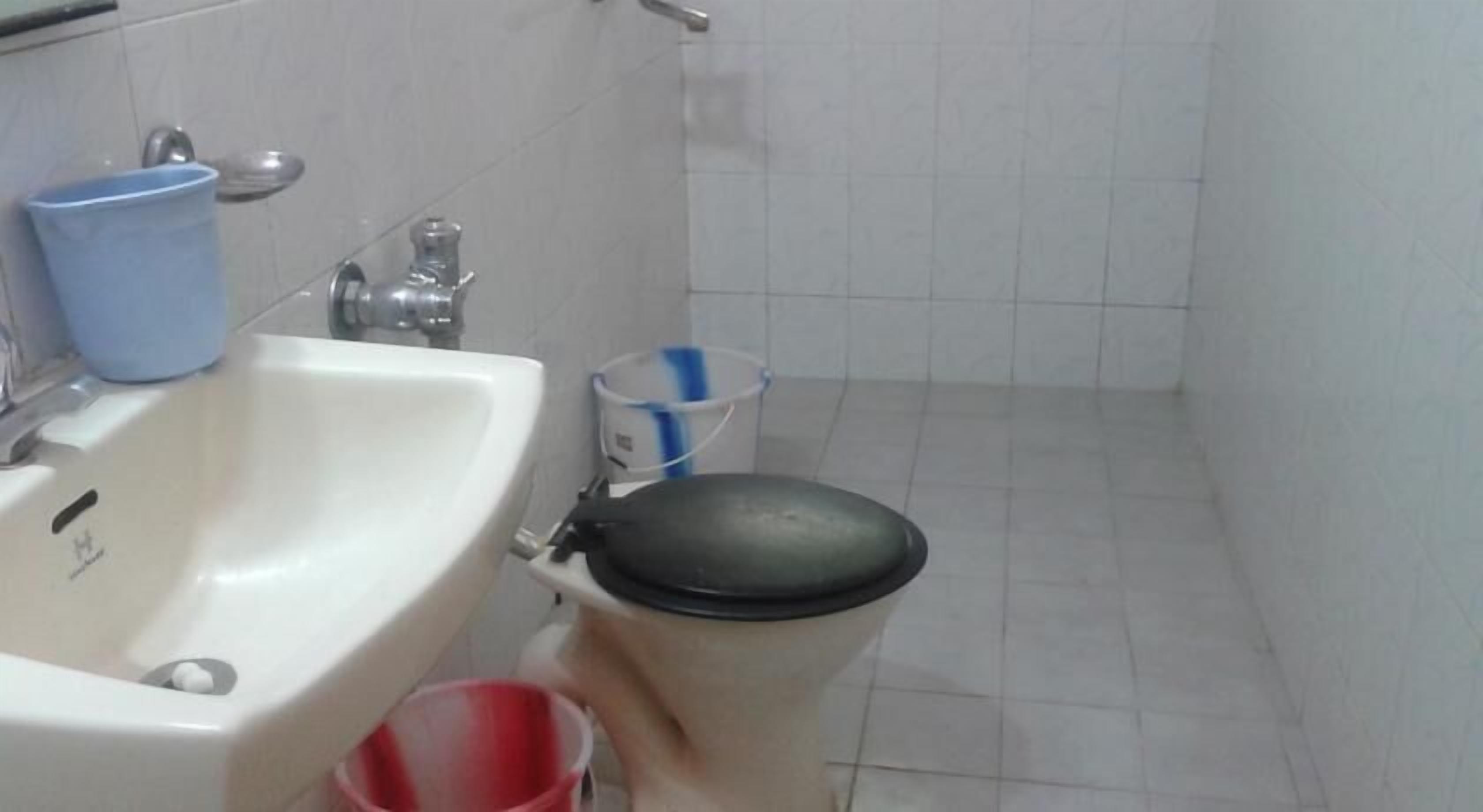 A bathroom with a sink, toilet, and a trash bin.