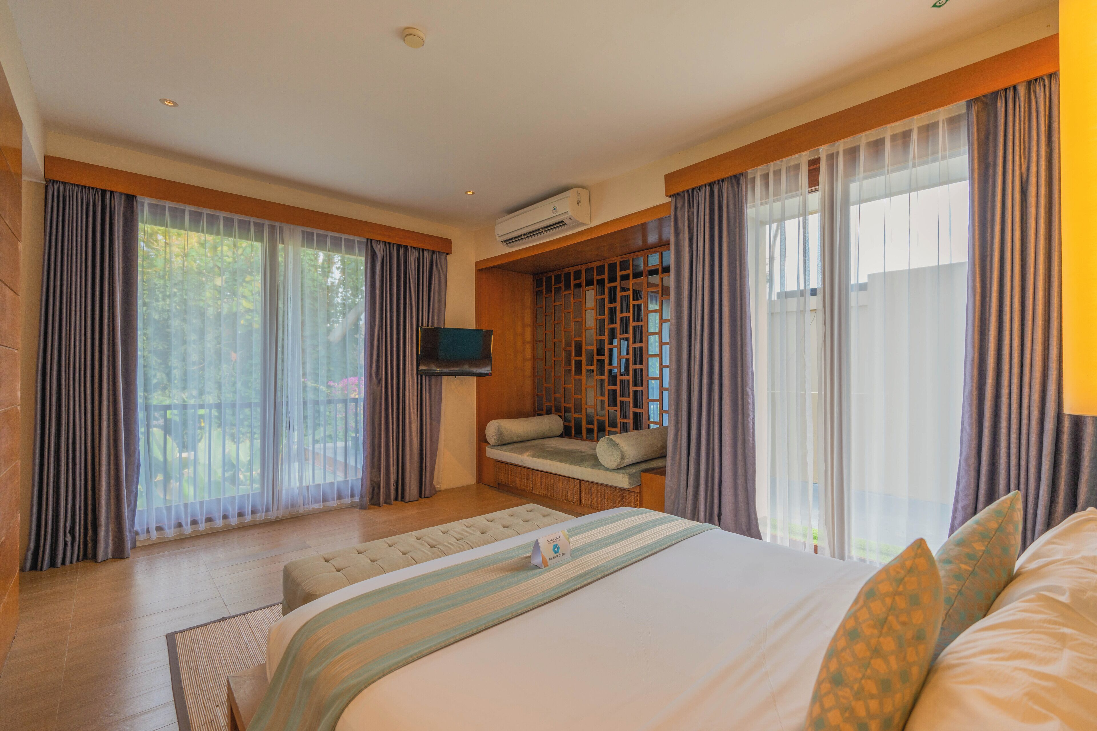 Una habitación de hotel moderna con una cama grande, un sofá, un televisor y un balcón con cortinas.