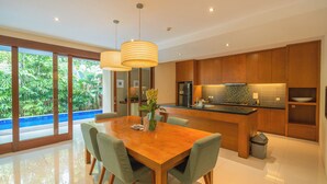 Una cocina moderna con armarios de madera, una isla central y un comedor con mesa y sillas de madera.