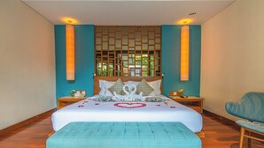 Habitación de hotel con una cama grande, cabecero de madera, dos mesitas de noche, una silla y un panel decorativo en la pared.
