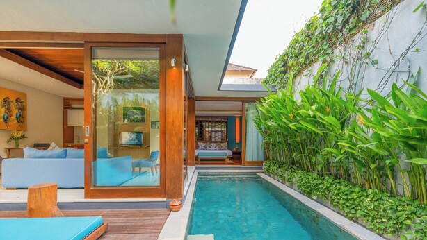 Una casa moderna con piscina, terraza de madera y sala de estar con sofá y sillones.
