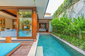 Una casa moderna con piscina, terraza de madera y sala de estar con sofá y sillones.