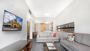A modern living room with a sofa, coffee table, and a flat-screen TV mounted on the wall.