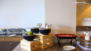 A breakfast buffet setup with bowls of food, a fruit tray, and a juice dispenser. - Naris Art Hotel (Pattaya)