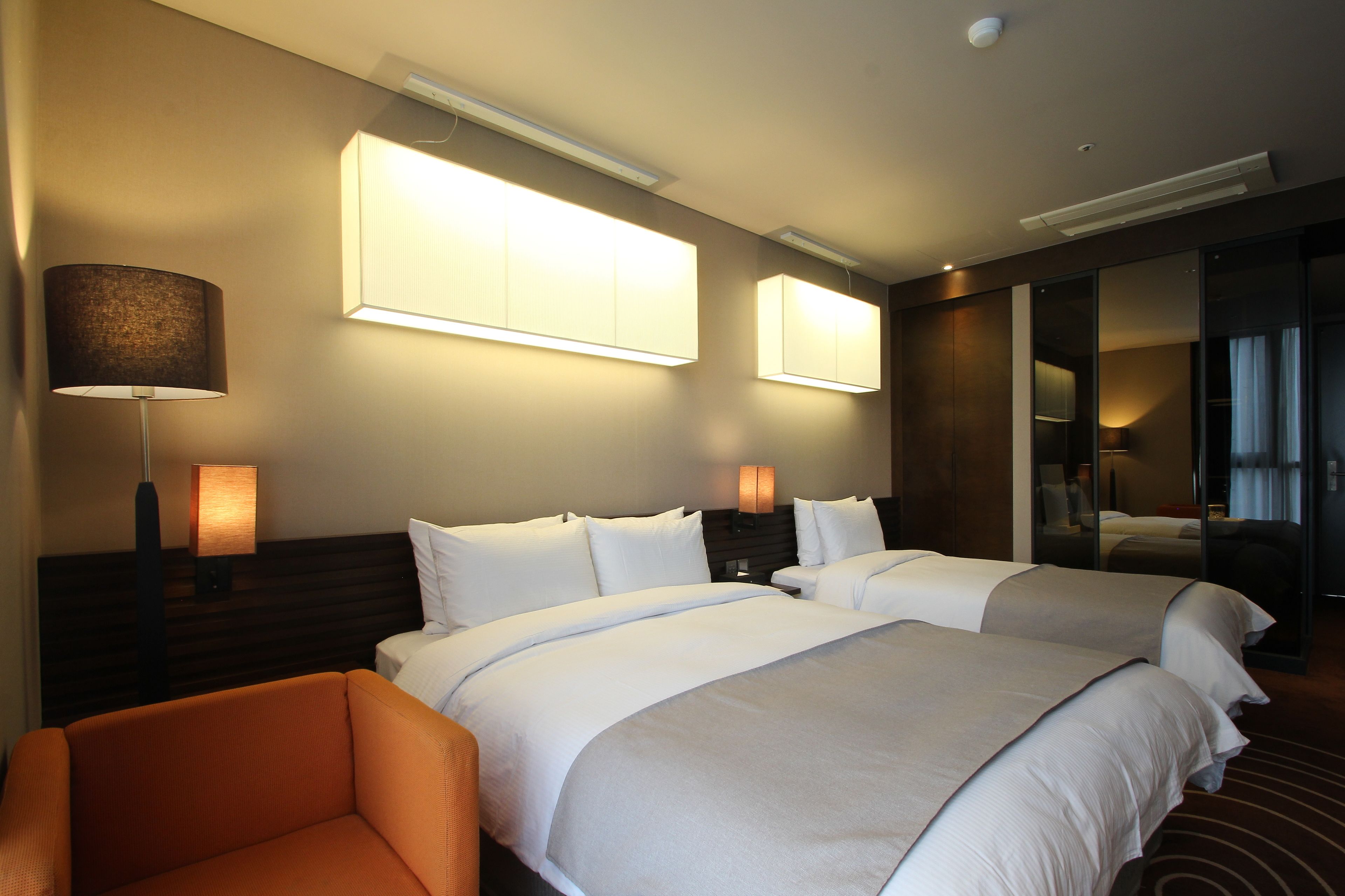 A hotel room with two beds, a sofa, and a desk.