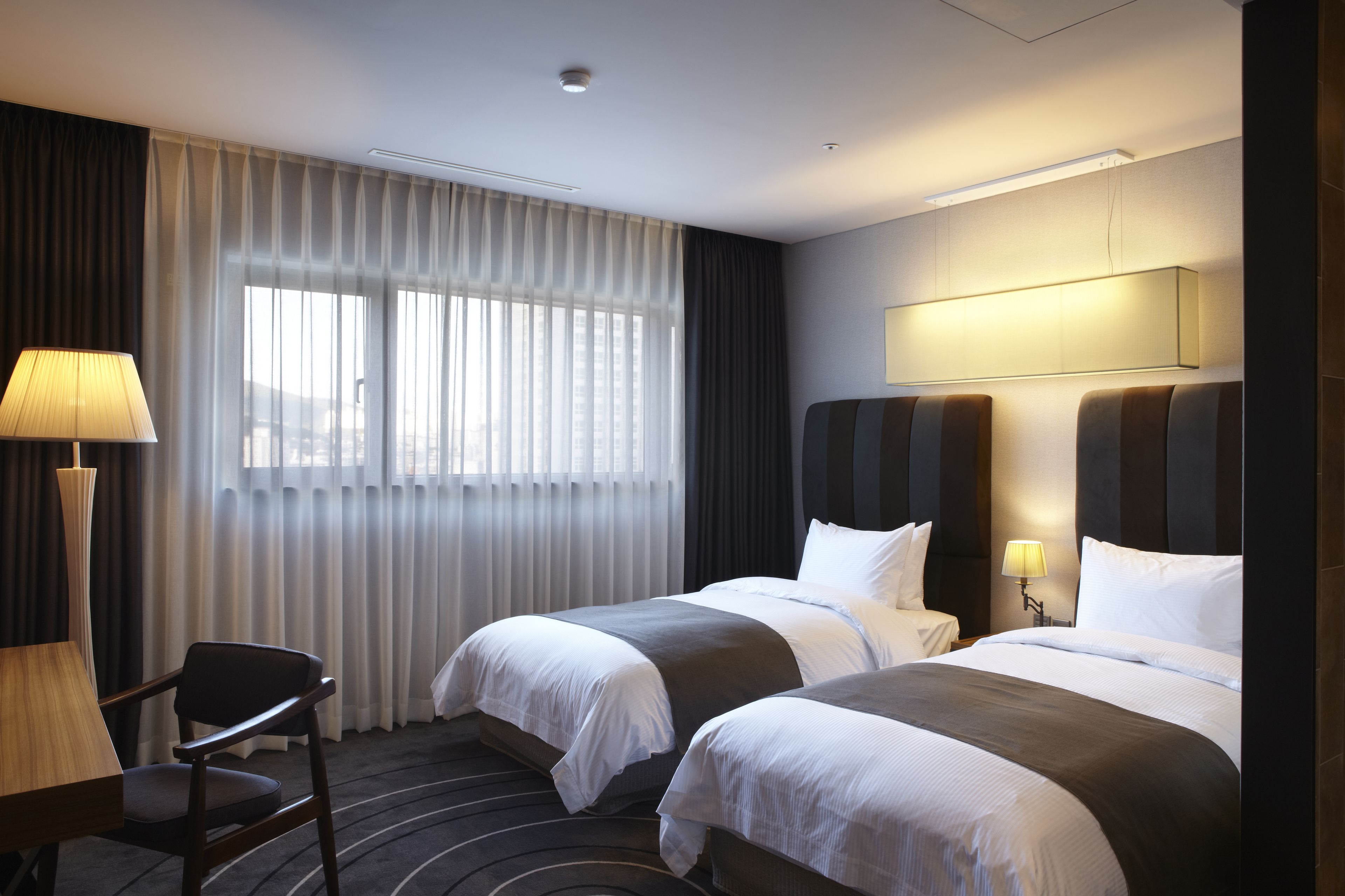 A hotel room with two beds, a desk, and a chair.