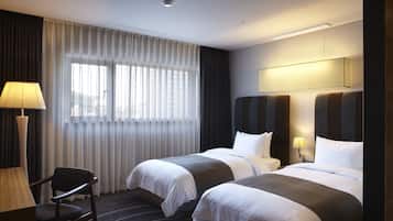 Une chambre d’hôtel avec deux lits, un bureau et une chaise.
