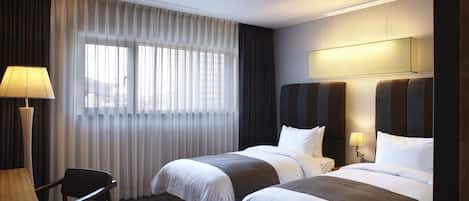 A hotel room with two beds, a desk, and a chair.