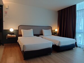 A hotel room with two beds, a bedside table with a phone, a wall-mounted light, and a window with curtains. - K Hotel (Kuala Lumpur)