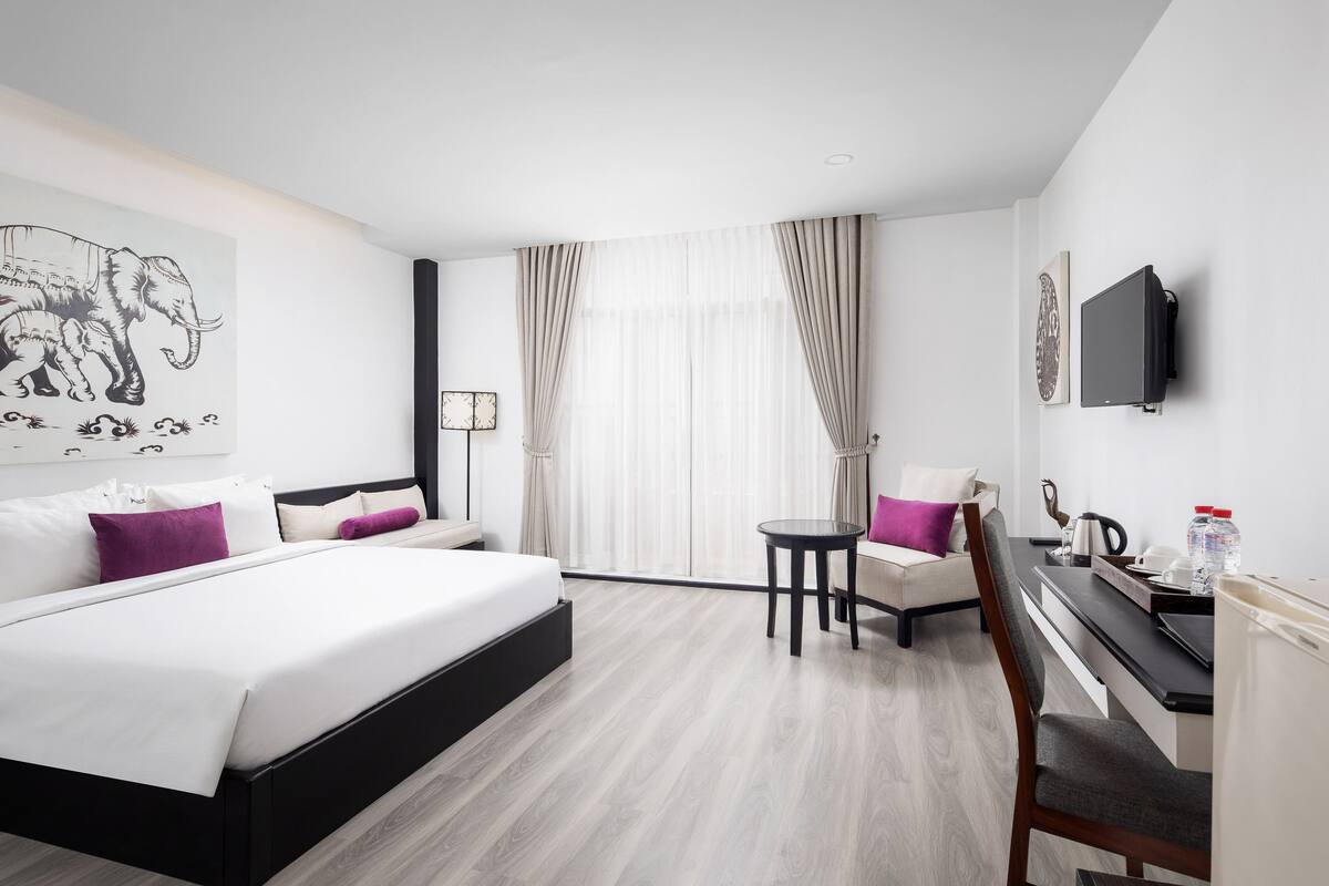 Ein Hotelzimmer mit einem großen Bett, einem Schreibtisch, einem Stuhl und einem Fernseher.