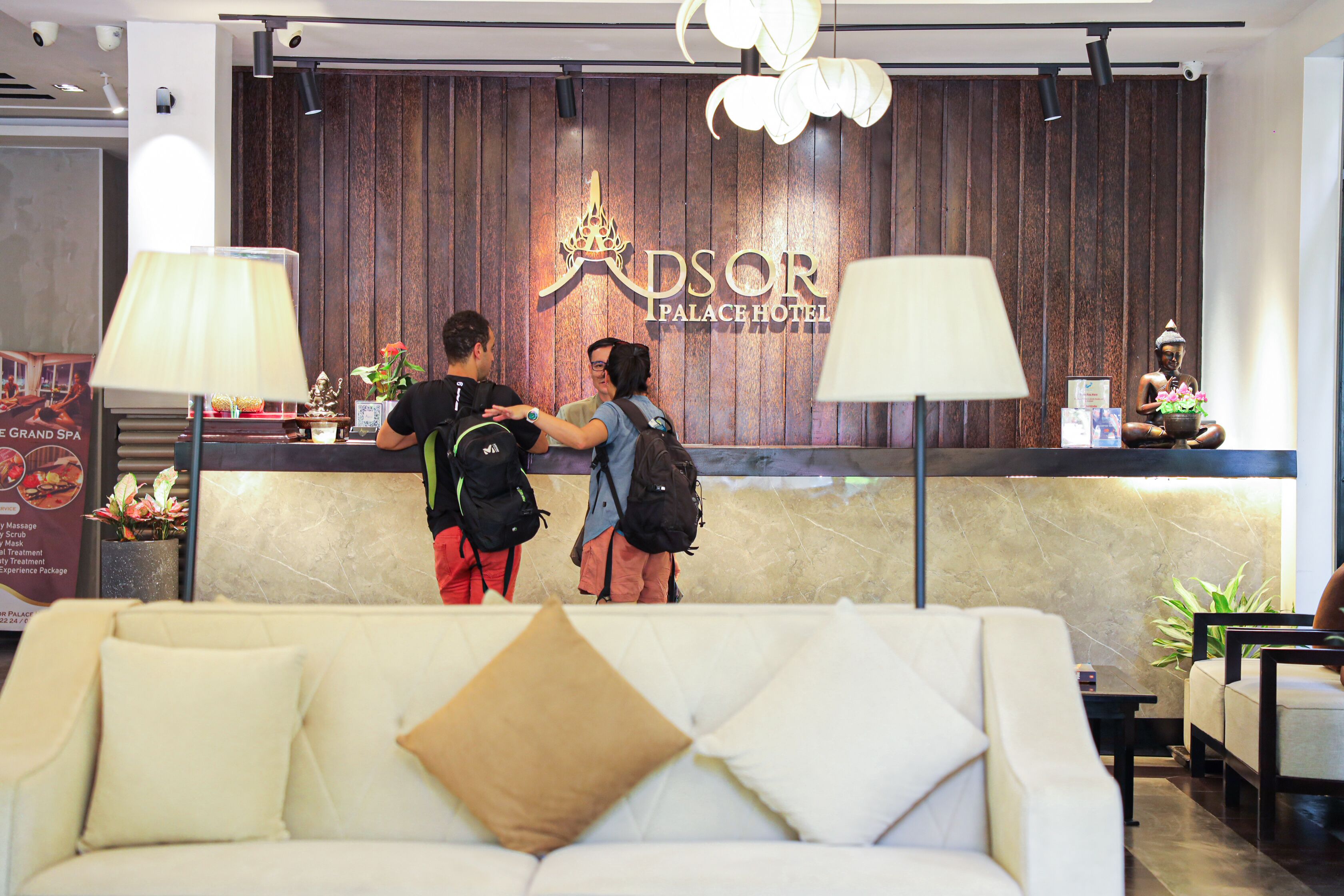 A reception area with a wooden wall, a reception desk, and a sofa in the foreground.