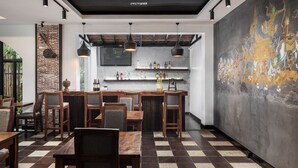 Ein Restaurant mit Schachbrettboden, Holztischen und -stühlen, einer Bar mit Flaschenregalen und einem großen Wandgemälde.