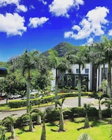 A modern building with a landscaped garden, palm trees, and a clear blue sky.